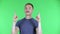 Portrait of a young man pointing up fingers and shaking his head approvingly. Cute male with a mustache in a blue t
