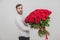 Portrait of a young man with a red roses bouquet, looking confused, because he dont know how to make a proposal.