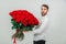 Portrait of a young man with a red roses bouquet, looking confused, because he dont know how to make a proposal.