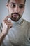 Portrait of a young man scratching his beard with a finger while he is thinking about something