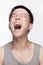 Portrait of young man screaming, mouth open, studio shot