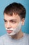 Portrait of young man with shaving foam ready to shave beard. indoor studio shot isolated on blue background