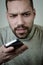 Portrait of a young man with a short beard engrossed in a cell phone conversation that worries him