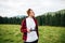 Portrait of a young man standing with a remote control in the mountains and flying on a drone  looking away. Shooting a drone in