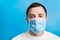 Portrait of young man wearing medical mask with epidemic word at blue background. concept. Respiratory protection