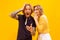 Portrait of young man and woman in casual clothes posing isolated over yellow studio background. Whispering excited news