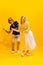 Portrait of young man and woman dancing, posing isolated over yellow studio background. Emotive dance
