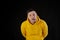 Portrait of young man in yellow hoodie with grimacing face. Close up of funny guy monkeying on black background.