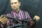 Portrait of a young mechanic in a plaid shirt on a black background in the process of work. A bicycle mechanic holds a tool and a