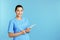 Portrait of young medical assistant with tablet on color background.