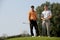 Portrait of young men standing with golf sticks on golf course