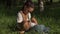 Portrait of young mother feeding baby in park, sitting on ground. Woman being playful with child while breastfeeding