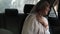 Portrait of a young muslim woman in beige headscarf, sitting in the car while looking out through the window and smiling