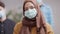 Portrait of young Muslim woman in coronavirus face mask with blurred people in queue at background. Multiracial people