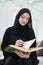Portrait of young muslim woman reading Quran in modern home