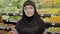 Portrait of young Muslim woman standing in grocery and looking at camera. Beautiful girl in hijab posing in supermarket