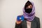 Portrait of young muslim woman wearing formal wear, protect face mask and hijab head scarf, hold Kosovo flag card against isolated