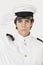 Portrait of young navy officer saluting against gray background