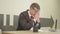 Portrait young nervous stressed busy man in formal wear and glasses sitting in the office in front of laptop rubbing his