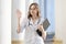 Portrait of a young nurse, student girl at a medical university stands with a phonendoscope and documents and waves her hand at