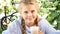 Portrait of a Young open-hearted girl sitting in a garden enjoying the sun. She holds a cup of hot chocolate, drinking