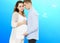 Portrait of young pair pending the kid isolated on blue background, Young attractive couple: pregnant mother and happy father,