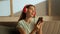 Portrait of young person in the room on the couch. Shot of female in headphones listening to music on smartphone