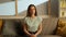 Portrait of young person in the room sitting on the couch. Woman sitting on the sofa looks at camera directly, tears in