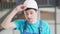 Portrait of young positive Caucasian brunette man with hazel eyes putting on hard hat and smiling looking at camera