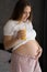 Portrait of young pregnant woman holding glass with orange juice at home, the happiest time for woman.