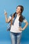 Portrait of young pretty cheerful woman student in t-shirt, denim clothes with backpack pointing index finger aside