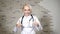 Portrait of young pretty doctor in brace wearing white medical gown showing thumbs up and signs of approval. Health care