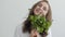 Portrait young pretty woman sniffing fresh greens standing at the table in modern kitchen. Concept of healthy food