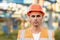 Portrait of Young Professional Heavy Industry Engineer Worker Wearing Safety Vest, Putting on Hardhat. In the Background