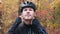 Portrait of young professional male cyclist in autumn park. Attractive motivated athlete in black helmet taking off glasses after