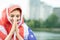 Portrait of young refugee woman with USA national flag on her head and shoulders. Positive muslim girl praying outdoors