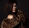 Portrait of young rich sexy brunette woman in leopard fur coat jacket with naked shoulders with expensive jewelry
