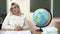 Portrait of a young school teacher at the table in the classroom with a globe