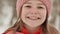 Portrait of a young schoolgirl with freckles in the woods in winter. The girl touches her nose with her hand in the