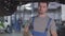 Portrait of young serious Caucasian man in blue workrobe standing under car in repair shop and looking at camera