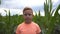 Portrait of young serious red-haired boy looking into camera against the background of corn field. Little ginger kid