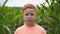 Portrait of young serious red-haired boy looking into camera against the blurred background of corn field. Little kid