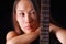 Portrait of a young sexual woman with Ð²rown,hair bare shoulders and guitar neck on a black background