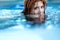 Portrait of young sexy woman with red hair, redhead swimming in the pool, head half submerged under water, copy space