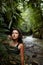 Portrait Young slender girl posing in the jungle hiding behind a palm leaf. Wildlife and a girl