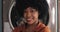 Portrait of young smiling African American woman standing in the self-service public laundry.