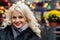 Portrait of a young smiling blonde woman against the background of defocused holiday lights. The concept of Christmas time. Copy