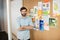 Portrait of young smiling businessman with arms crossed by soft board at office