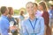 Portrait of young smiling businesswoman standing while holding wine glass against colleagues at success party on rooftop