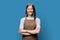 Portrait of young smiling confident woman in apron on blue background